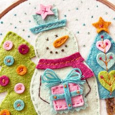 a close up of a embroidery on a piece of cloth with snowman and tree