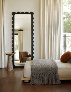 a bedroom with a bed, mirror and chair in it