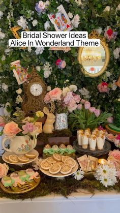 a table topped with lots of desserts and pastries next to a flower covered wall