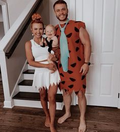 a man and woman dressed up as the flintstones with a baby in their arms