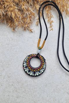 a necklace that has been made to look like a circular beaded pendant on a black cord