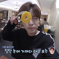 a young man is holding up an orange slice to his eye