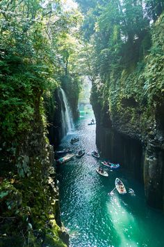 several boats floating in the water near a waterfall