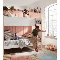 a girl jumping in the air on top of a bunk bed next to a child's bed