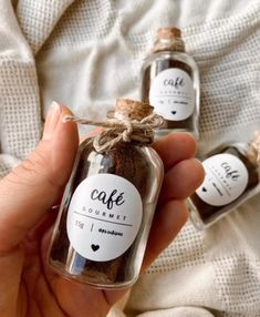 someone is holding two small jars with cinnamons in them, one has a label that says cafe gourmet