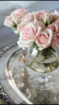 a glass vase filled with pink roses on top of a silver tray