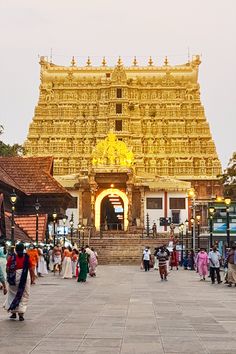 people are walking around in front of a large building that has a golden structure on it