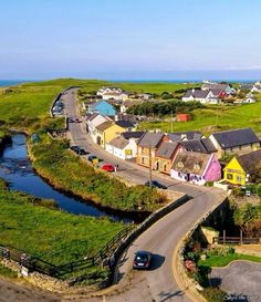 an aerial view of a small town by the ocean with cars driving on the road