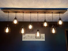 several light bulbs hanging from the ceiling above a sign that reads, beauty by design