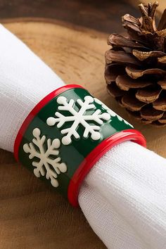 a napkin holder with snowflakes on it and a pine cone in the background