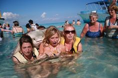 three women are in the water with one woman on her back and two others behind them