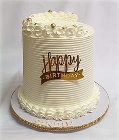 a birthday cake with white frosting and gold trimmings on a platter