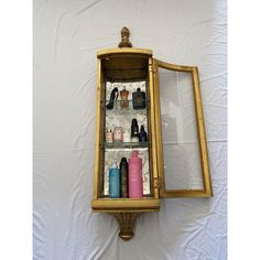 a gold framed display case with bottles and other items in it on a white background