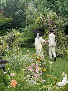 a bride and groom walking through the garden