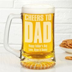 a beer mug with the words cheers to dad on it next to pretzels