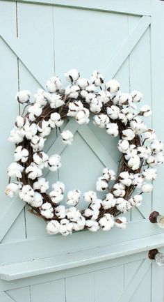 a wreath made out of cotton is hanging on the side of a blue barn door