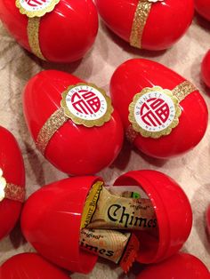 several red eggs with gold trim and chinese writing on them, all lined up next to each other