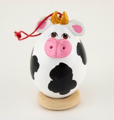 a white and black cow figurine with a red ribbon on it's head