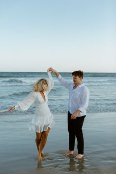 a man and woman dancing on the beach