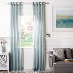 a living room with a couch, chair and window covered in blue drapes on the windowsill