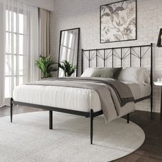 a bedroom with white brick walls and wood flooring, a large mirror on the wall above the bed