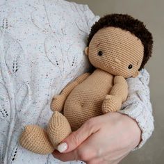 a person holding a small stuffed animal in their arms and wearing a knitted sweater