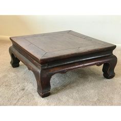 an old wooden coffee table on carpeted floor