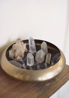 some rocks are sitting in a bowl on a wooden table next to a white wall