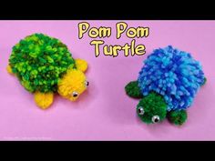 two pom pom turtle made out of yarn on top of a pink surface