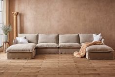 a living room with wooden floors and a beige couch on the floor next to a large window