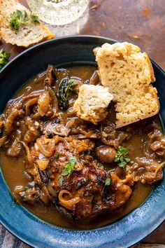 a blue plate topped with meat and mushrooms covered in gravy next to bread