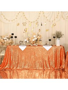 the table is set up with gold sequins and white flowers in vases