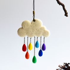 a felt cloud with rain drops hanging from it's side on a tree branch