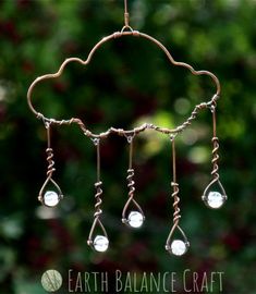 a wind chime hanging from a tree branch with beads and glass drops on it