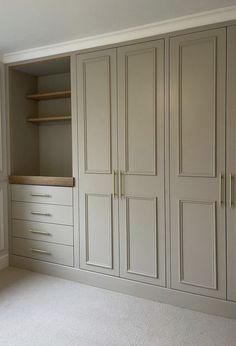 an empty room with white cupboards and shelves in the corner, next to a window