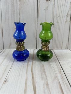 two colorful glass vases sitting on top of a white wooden table next to each other