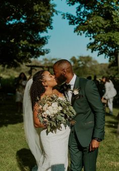 a bride and groom kissing in the grass