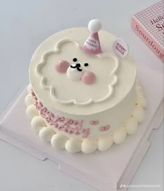 a white cake with pink frosting and a bear decoration on the top is sitting on a plastic tray