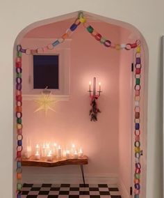 candles are lit in the corner of a room with a checkered floor and pink walls