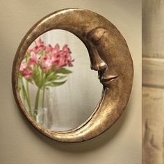 a mirror that is hanging on the side of a wall next to a vase with flowers in it