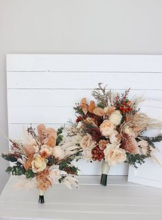 two vases filled with flowers sitting on top of a white shelf next to each other