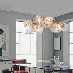 a modern chandelier hangs over a dining room table with chairs and artwork on the walls