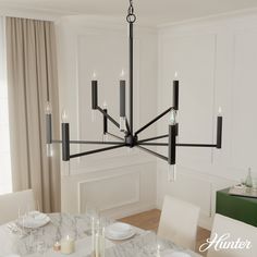 a chandelier hanging over a dining room table with white plates and silverware