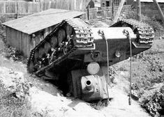 an old tank sitting on top of a dirt hill next to a wooden fence and building