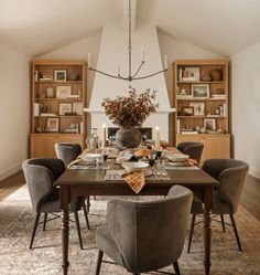 the dining room table is set with place settings and candles in front of bookshelves