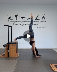 a woman doing a handstand on top of a desk in front of a wall