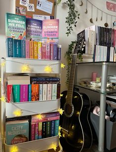 a book shelf filled with books next to a guitar