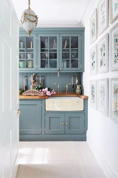 a kitchen with blue cabinets and pictures on the wall above it, along with a chandelier