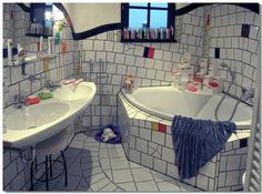 a bathroom with two sinks and a bathtub in it's corner, surrounded by tiled walls