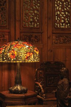 a table lamp sitting on top of a wooden table next to a vase and chair